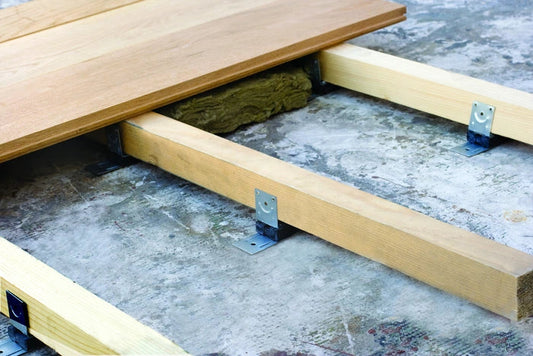 Wooden floor joists with insulation on a concrete surface.