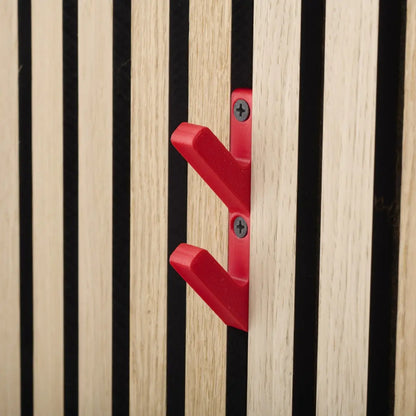 Close-up of a red double coat hook attached to a wooden slat wall with black gaps.