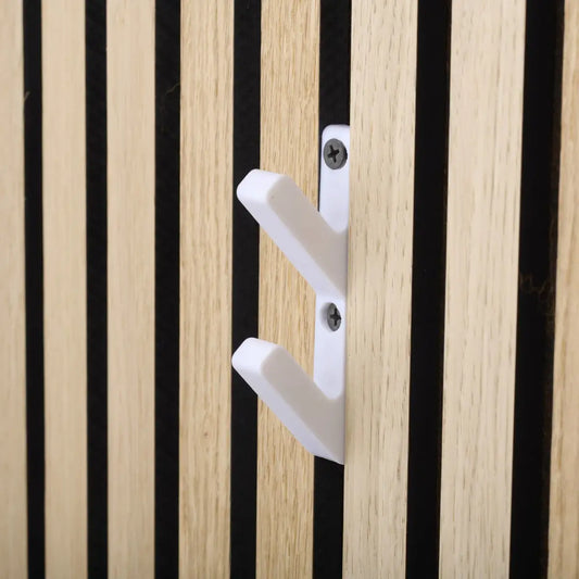 Close-up of a white, double-pronged hook mounted on a wooden wall with alternating light and dark vertical panels. 
