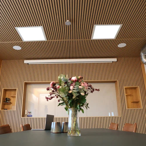 Meeting room with wood slat walls and ceiling, flowers on table.