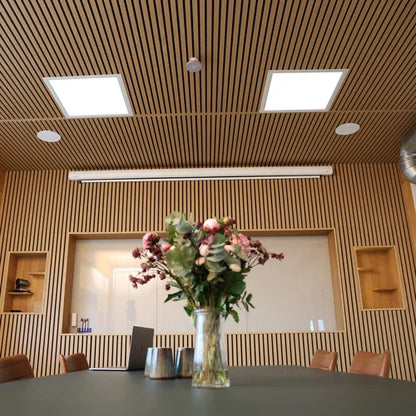 Meeting room with wood slat walls and ceiling, flowers on table.
