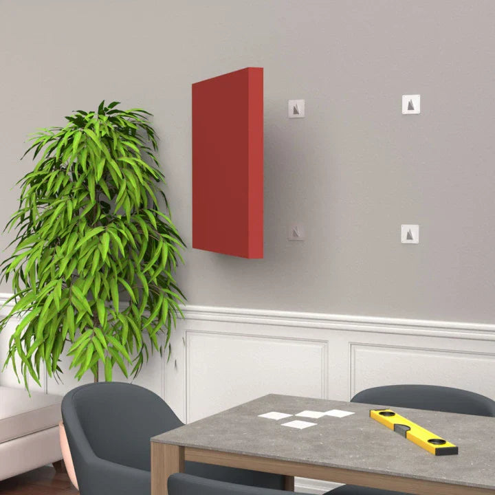Interior room with red wall art, plant, gray chairs, and a table with a level and white squares on top.