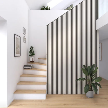 Bright and airy interior with wood stairs and floors, black and white paneled wall, and indoor greenery.

