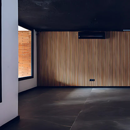 Modern interior with dark floors, slatted wood wall, black ceiling, and a window showing a brick wall.
