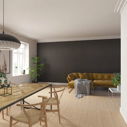 Well-lit living and dining area with a mustard-colored sofa, wooden dining table, and matching chairs against a dark gray paneled wall and light wood flooring.