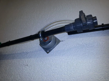 Black pipe with a gray valve connected to a wall with a silver bracket.