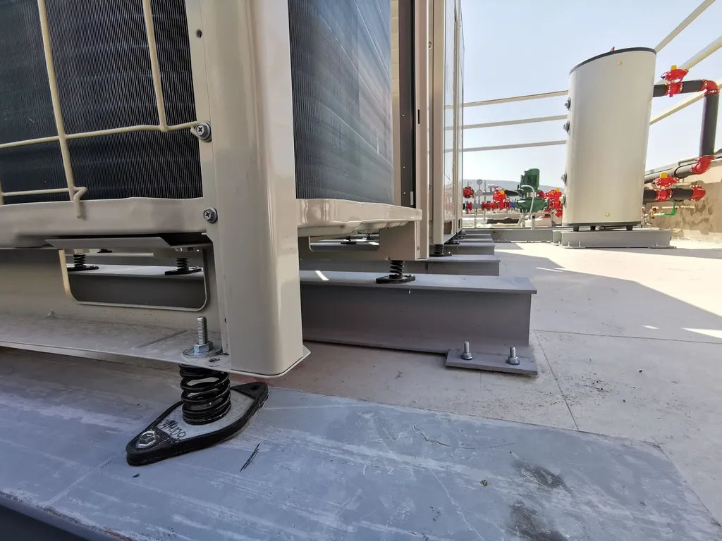 Close-up on rooftop HVAC unit supports with spring isolators.
