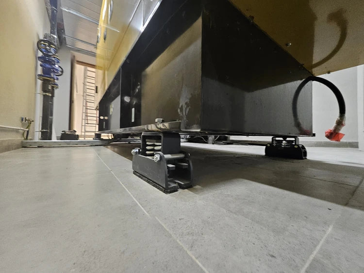 Industrial equipment with black, shock-absorbing mounts on a tiled floor.