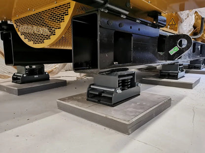 Industrial machinery supported by anti-vibration mounts on concrete pads.