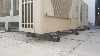 Several large air conditioning units resting on vibration isolation mounts on a tiled surface.