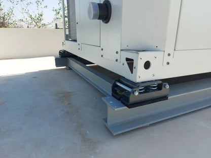 Large white industrial generator with black spring vibration isolators mounted on gray steel I-beams on a concrete roof.