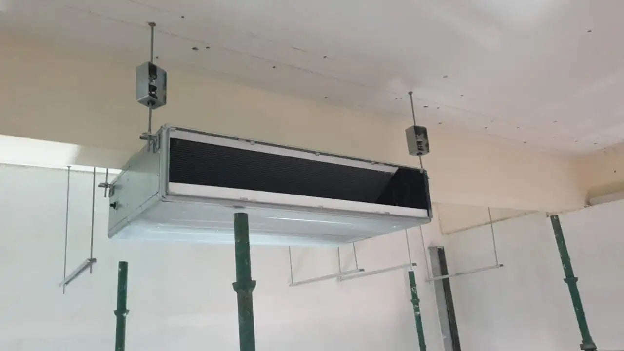 Underside view of an installed, rectangular, industrial air conditioner unit.