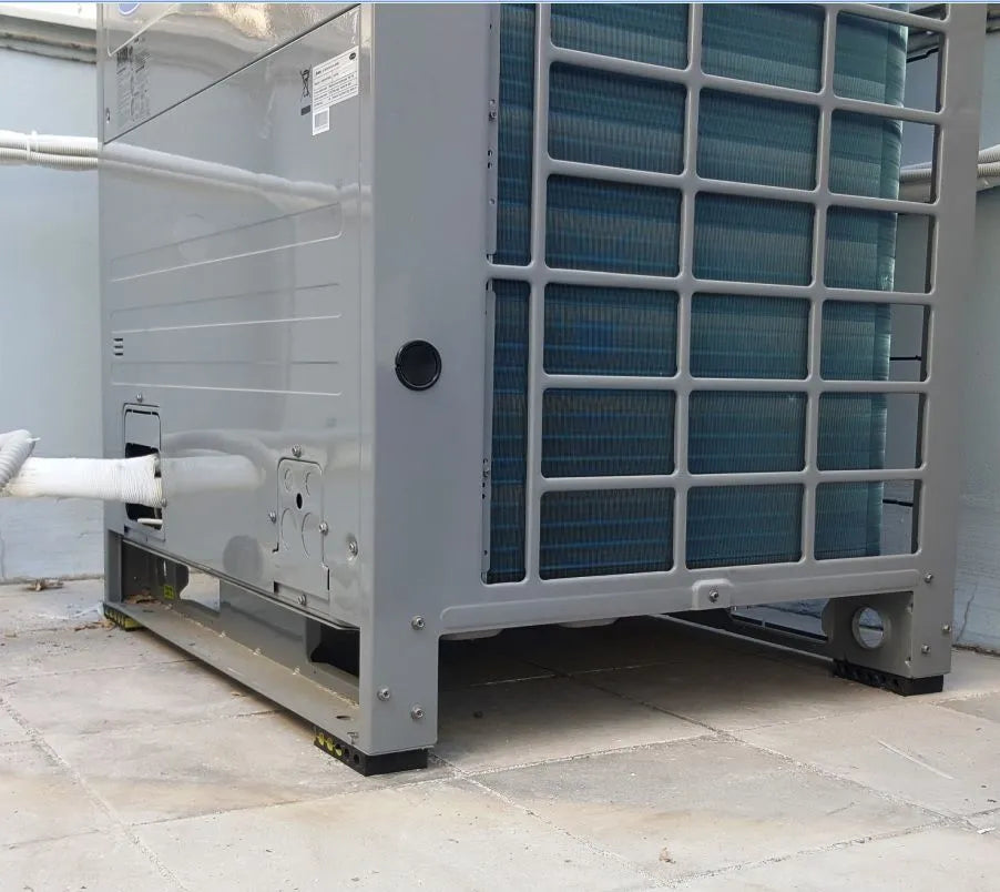 A gray commercial air conditioning unit sits on a tiled surface.
