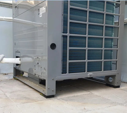 A gray commercial air conditioning unit sits on a tiled surface.