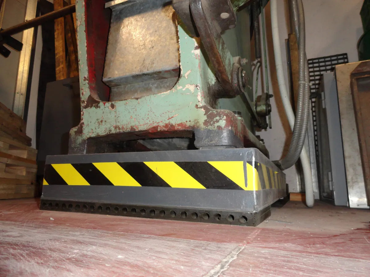 Close-up of an industrial machine base with yellow and black safety stripes.