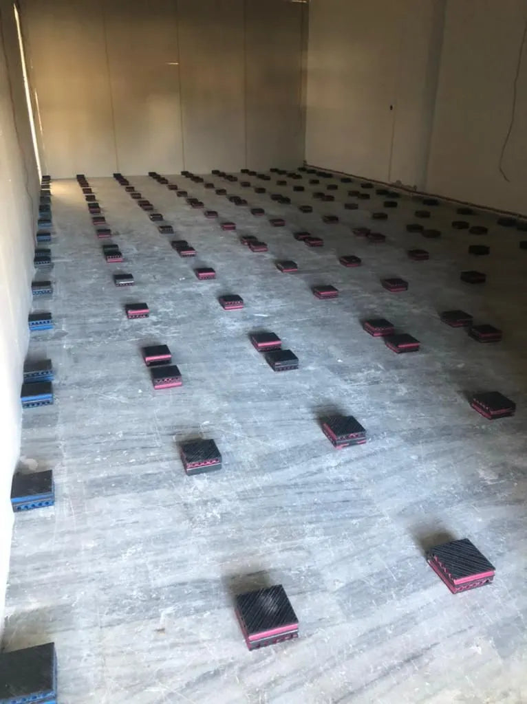 A room with concrete floors and square pads arranged in rows.