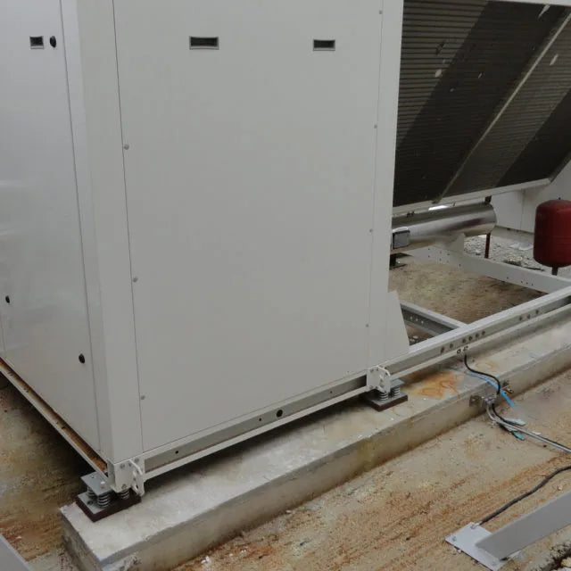 Industrial air conditioning unit mounted on springs on a rooftop.