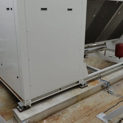 Industrial air conditioning unit mounted on springs on a rooftop.