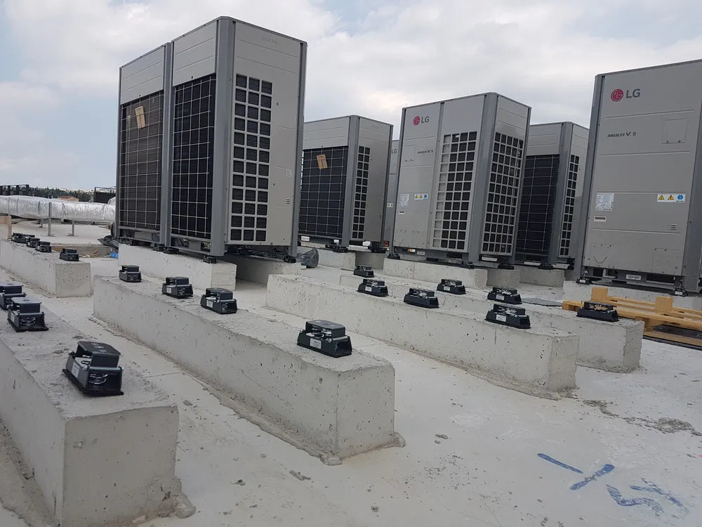 Several large, gray LG air conditioning units atop concrete bases on a flat roof.