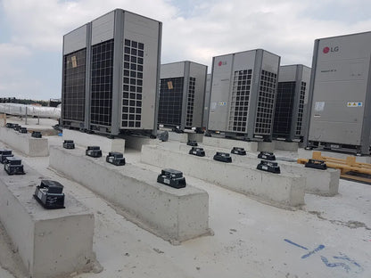Several large, gray LG air conditioning units atop concrete bases on a flat roof.