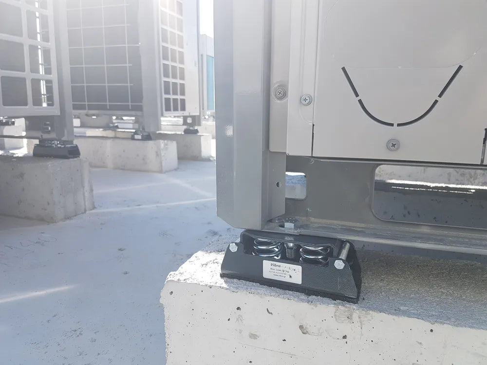 Rooftop HVAC equipment mounted on concrete pads with vibration isolators.