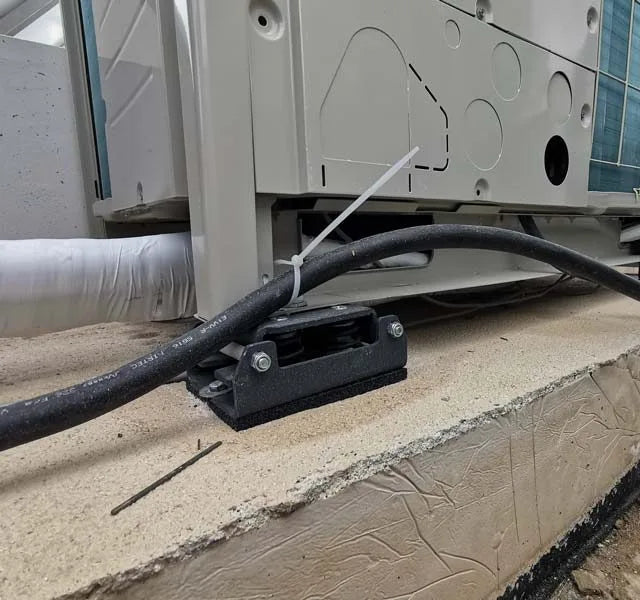 Outdoor HVAC system with black cable secured by zip tie.