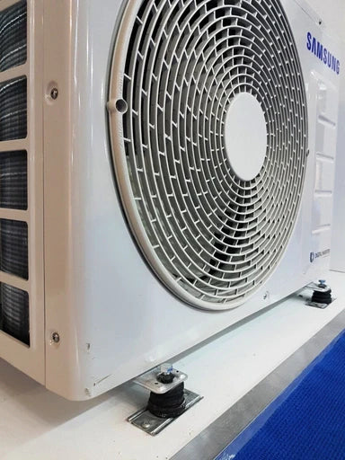 Close-up of a white Samsung air conditioner unit with a circular fan grill, mounted on shock absorber feet.