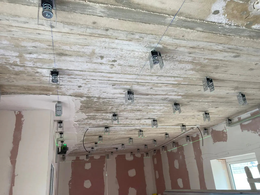 Interior renovation with ceiling hangers, exposed concrete, and laser levels.
