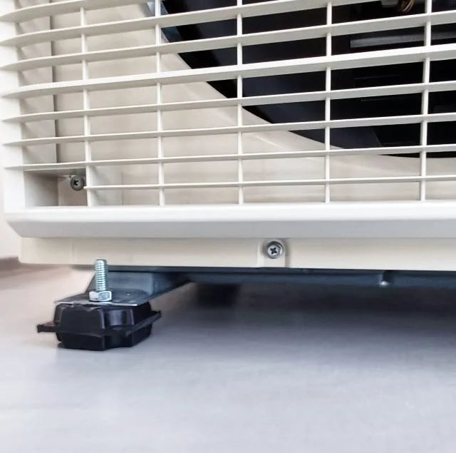 Close-up of an air conditioner's base, showing a black rubber foot with a bolt and washer.