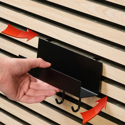 Hand interacting with a black metal key rack on a slatted wood wall.