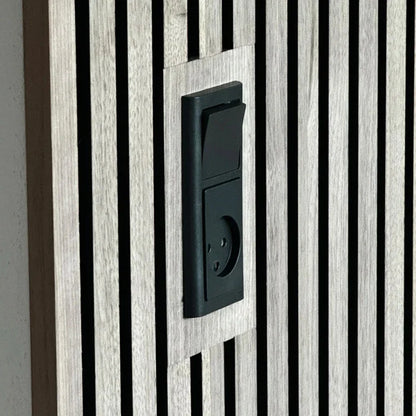 Close-up of a black electrical switch and outlet mounted on a wooden slat wall.