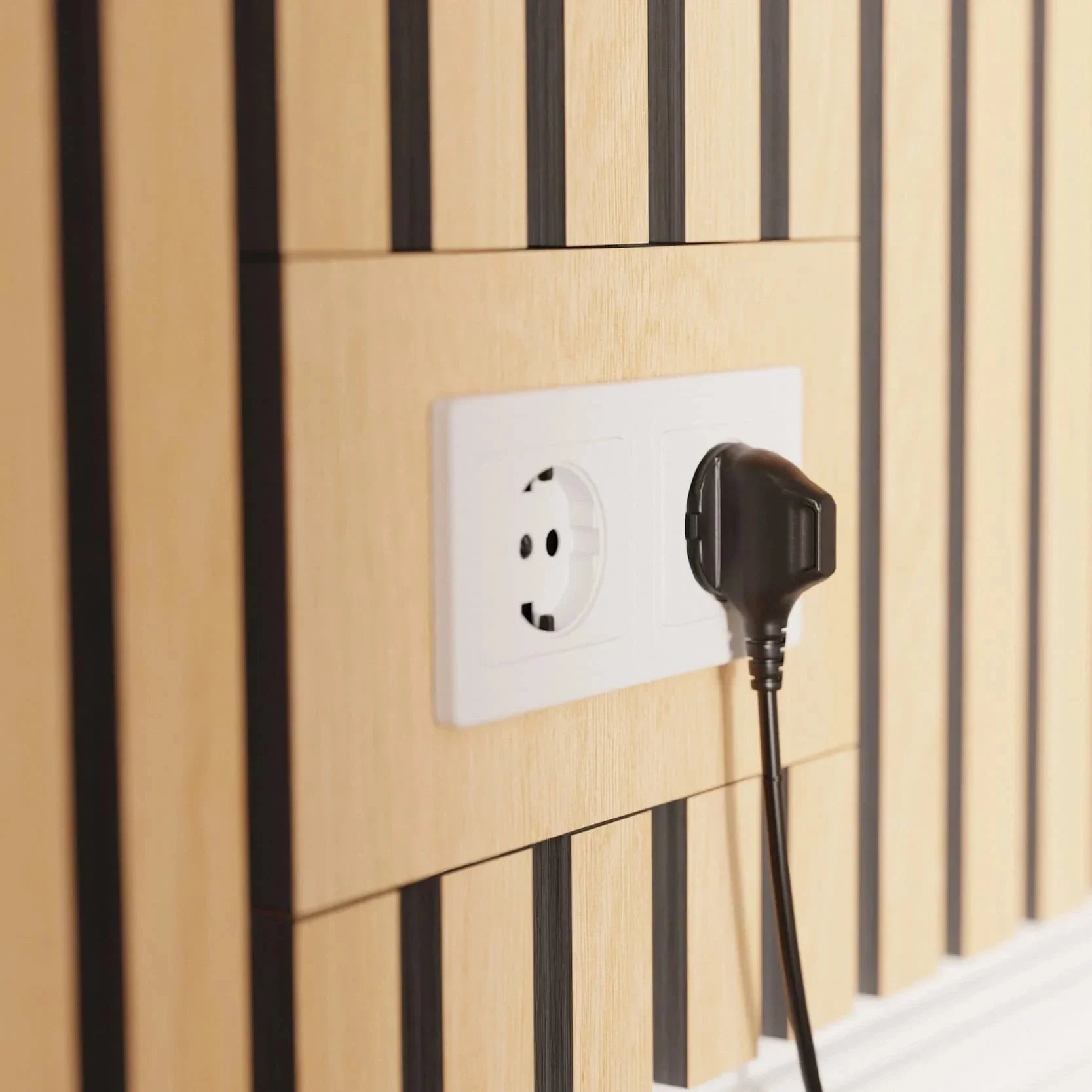 A black plug inserted into a white electrical outlet on a light brown and black wood paneled wall.